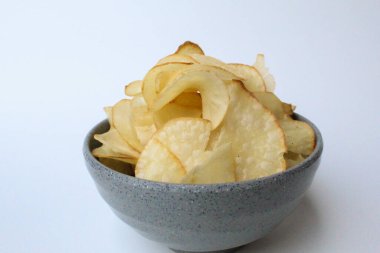 Tapyoka cipsi, ya da manyok cipsi, ya da kızartılmış manyok kökü. Gri bir kasede. Beyaz arkaplanda izole edilmiş