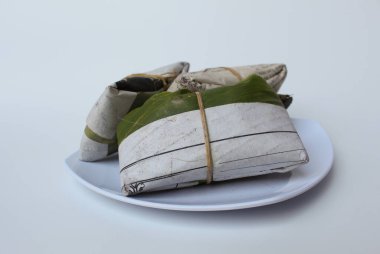 Tempeh ya da tempe, işlenmiş soya ürünü, muz yaprağı ve gazete kağıdına sarılı. Beyaz arkaplanda izole