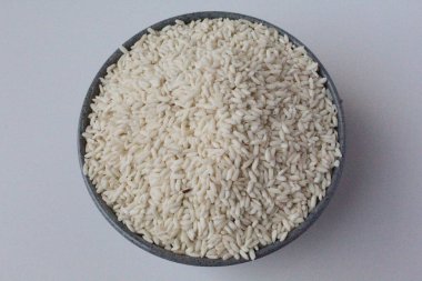 Gri kasenin içinde beyaz arka planda izole edilmiş bir pirinç yığını.