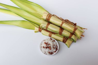 Lepet, Endonezya 'dan geleneksel aperatif, glutinous pilavı, soya fasulyesi ve rendelenmiş hindistan cevizi. Genç palmiye yapraklarına sarılmış. Pişmeden önce. Beyaz arkaplanda izole