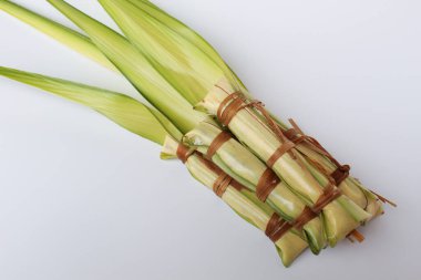 Lepet, Endonezya 'dan geleneksel aperatif, glutinous pilavı, soya fasulyesi ve rendelenmiş hindistan cevizi. Genç palmiye yapraklarına sarılmış. Pişmeden önce. Beyaz arkaplanda izole