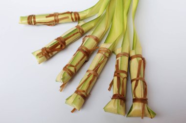 Lepet, Endonezya 'dan geleneksel aperatif, glutinous pilavı, soya fasulyesi ve rendelenmiş hindistan cevizi. Genç palmiye yapraklarına sarılmış. Pişmeden önce. Beyaz arkaplanda izole