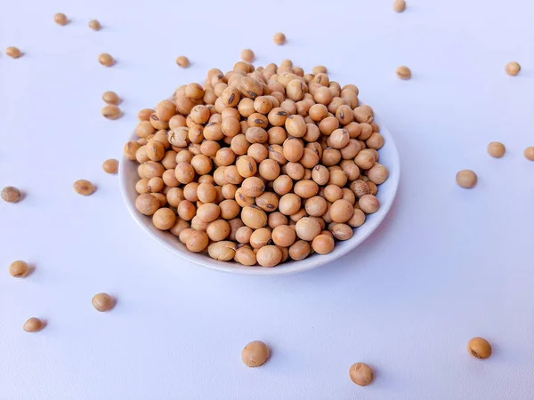 Dried Glycine max or soybean or soyabean, inside a white plate, isolated in white background