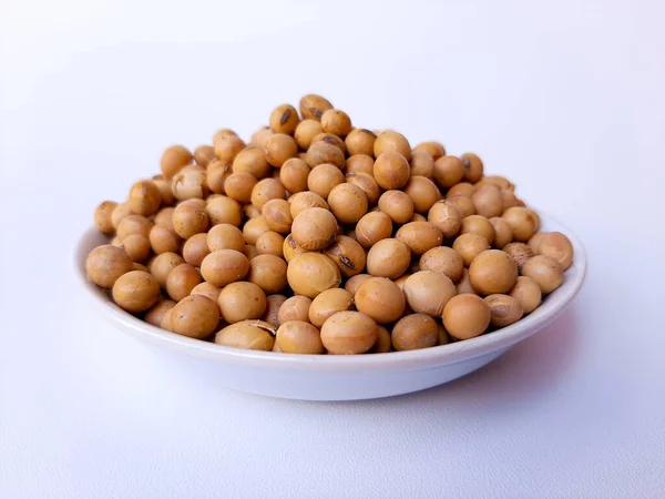 Dried Glycine max or soybean or soyabean, inside a white plate, isolated in white background