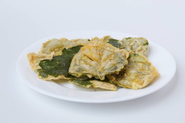 Kızarmış yeşil amaranth yaprakları ya da ıspanak yaprakları, beyaz bir tabakta un hamuru ile kaplıdır. Beyaz arkaplanda izole.