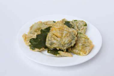 Kızarmış yeşil amaranth yaprakları ya da ıspanak yaprakları, beyaz bir tabakta un hamuru ile kaplıdır. Beyaz arkaplanda izole.