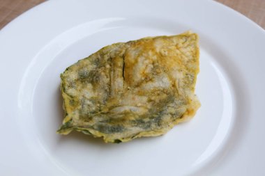 Kızarmış yeşil amaranth yaprakları veya ıspanak yaprakları, beyaz bir tabakta un hamuru ile kaplıdır..