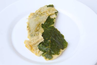 Kızarmış yeşil amaranth yaprakları ya da ıspanak yaprakları, beyaz bir tabakta un hamuru ile kaplıdır. Beyaz arkaplanda izole.