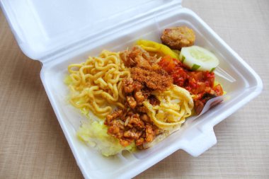 Nasi kuning, Endonezya 'dan geleneksel bir yemektir. Sarı pirinç, erişte, tavuk ipi, omlet ve çeşitli mezelerden oluşur. Satılık köpük kutusuna yerleştirilmiş..