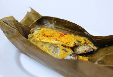 Pepes ikan, ya da muz yaprağına sarılı haşlanmış balık. Geleneksel Endonezya yemekleri. Beyaz bir tabakta.