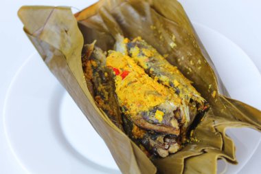 Pepes ikan, ya da muz yaprağına sarılı haşlanmış balık. Geleneksel Endonezya yemekleri. Beyaz bir tabakta.