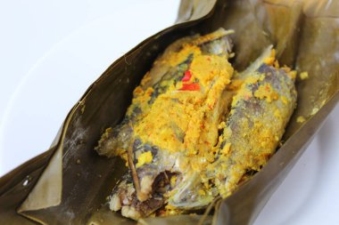 Pepes ikan, ya da muz yaprağına sarılı haşlanmış balık. Geleneksel Endonezya yemekleri. Beyaz bir tabakta.
