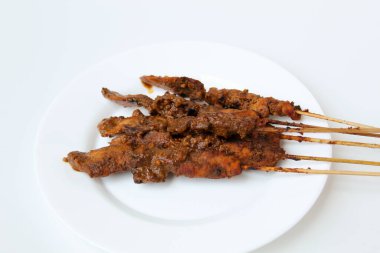 Fıstık soslu tavuk kanadı, bambu şiş. Endonezya geleneksel yemekleri. Beyaz bir tabakta. Beyaz arkaplanda izole