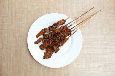 Fıstık soslu tavuk kanadı, bambu şiş. Endonezya geleneksel yemekleri. Beyaz bir tabakta. Beyaz arka planda izole edilmiş. Düz ya da üst görünüm