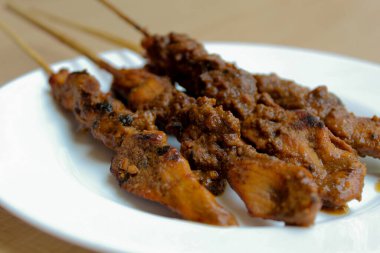 Fıstık soslu tavuk kanadı, bambu şiş. Endonezya geleneksel yemekleri. Beyaz bir tabakta. Beyaz arkaplanda izole