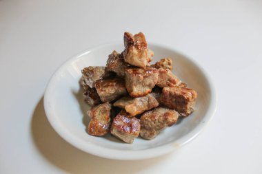 Beyaz arka planda izole edilmiş, küçük bir tabakta doğranmış biftek.