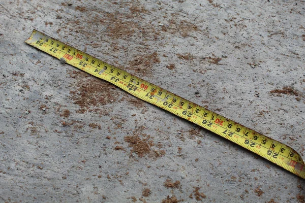 Yellow measuring tape or construction measuring tape, on concrete background