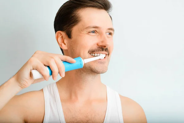 Schöner Lächelnder Junger Mann Beim Zähneputzen Mit Moderner Elektrischer Zahnbürste Stockbild