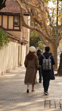 Yürüyen insanlarla yol manzarası ve şehirde sıcak güneş ışığı. 
