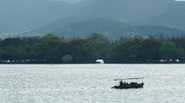 Baharda Çin 'in Hangzhou şehrindeki güzel göl manzaraları. Huzurlu göl ve taze yeşil dağlar.