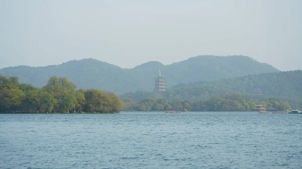 Baharda Çin 'in Hangzhou şehrindeki güzel göl manzaraları. Kıyıda eski bir tapınak kulesi bulunuyor.