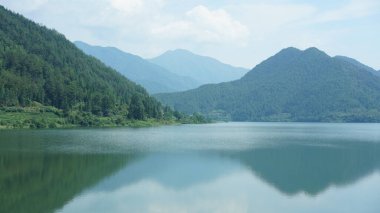 Çin 'in kırsal kesimindeki yeşil dağlarla çevrili güzel göl manzaraları.
