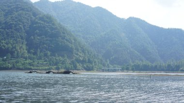 Çin 'in kırsal kesimindeki yeşil dağlarla çevrili güzel göl manzaraları.