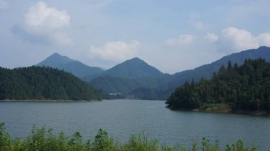 Çin 'in kırsal kesimindeki yeşil dağlarla çevrili güzel göl manzaraları.