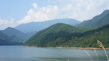 Çin 'in kırsal kesimindeki yeşil dağlarla çevrili güzel göl manzaraları.
