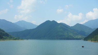 Çin 'in kırsal kesimindeki yeşil dağlarla çevrili güzel göl manzaraları.