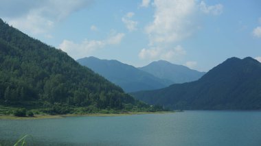 Çin 'in kırsal kesimindeki yeşil dağlarla çevrili güzel göl manzaraları.