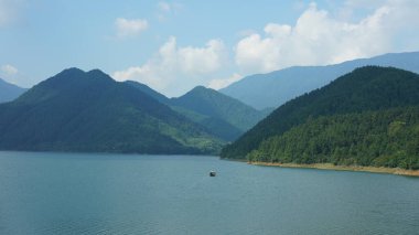 Çin 'in kırsal kesimindeki yeşil dağlarla çevrili güzel göl manzaraları.