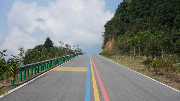 Arka planda mavi gökyüzü ve dağlar olan renkli bir yol manzarası