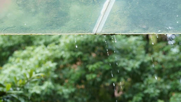 The glass window covered by the rain droplets and waterfall in the rainy day