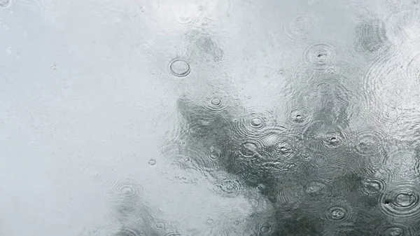 The glass window covered by the rain droplets and waterfall in the rainy day