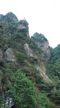 Yeşil ormanlı güzel dağlar ve Çin 'in kırsal kesimindeki bir uçurumun üzerine inşa edilmiş tahta bir yol.