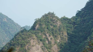 Yeşil ormanlı güzel dağlar ve püsküren kaya uçurumları Çin 'in kırsal kesimlerinde arka plan olarak kullanılıyor.