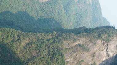Yeşil ormanlı güzel dağlar ve püsküren kaya uçurumları Çin 'in kırsal kesimlerinde arka plan olarak kullanılıyor.