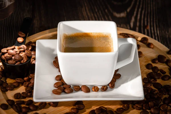 Xícara branca e pires de café expresso em um fundo de grãos de café espalhados. Fazendo café. — Fotografia de Stock