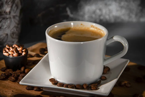 Xícara branca e pires de café expresso em um fundo de grãos de café espalhados. Fazendo café. — Fotografia de Stock