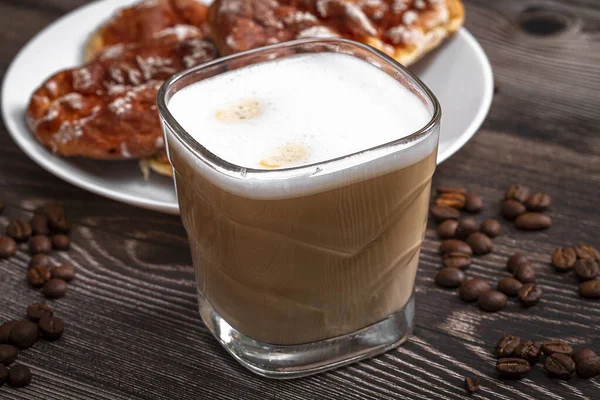Egy csésze márkás kávé egy kávébabos jelenetben és egy fából készült asztallap. A cappuccino elkészítése. — Stock Fotó