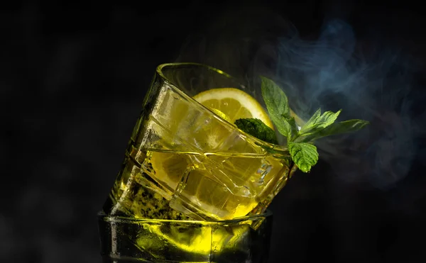 Koktail dengan es, mint segar dan sepotong segar lemon pada latar belakang gelap. Koktail. — Stok Foto