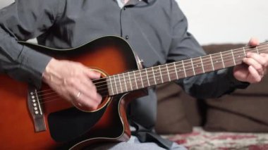 Yaşam tarzı konsepti. Müzisyen evdeki oturma odasında gitar çalar. Şarkı ve müzikle rahatla. Akustik gitar çalan bir adam eğlenir. Müzik.