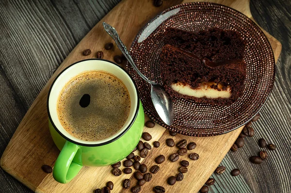 木製のテーブルの上にチョコレートケーキとコーヒーの緑のカップ 上からの眺め — ストック写真