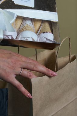 Bir kadın el yapımı şekerlemeleri bir kesekağıdının içine koyar. Waffle külahında marşmelov. Bir gül şeklinde yapılmıştır. Yakın çekim..