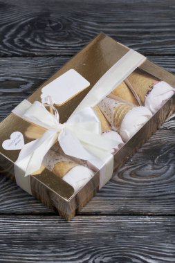 El yapımı bir kutuda ev yapımı şekerlemeler. Fiyonka bağlanmış bir kurdeleyle bağlanmış. Waffle külahında marşmelov. Bir gül şeklinde yapılmıştır. Yakın çekim..