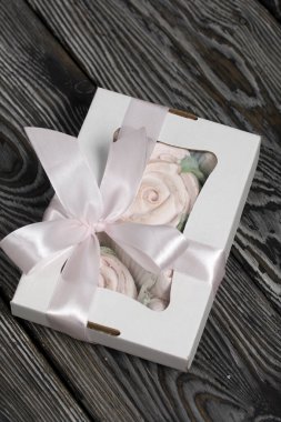 El yapımı ambalajlarda ev yapımı şekerlemeler. Gül şeklinde bir Zephyr. Çam ağacının arka planında.