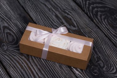 El yapımı ambalajlarda ev yapımı şekerlemeler. Gül şeklinde bir Zephyr. Çam ağacının arka planında.