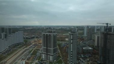 Modern çok katlı binaların yapımı. Yeni bir şehir bloğu inşaatı. İnşaat halindeki binalar ve kule vinçleri. Bulutlu havada hava fotoğrafçılığı.