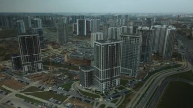 Modern çok katlı binaların yapımı. Yeni bir şehir bloğu inşaatı. İnşaat halindeki binalar ve kule vinçleri. Bulutlu havada hava fotoğrafçılığı.